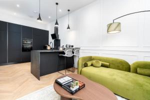 a living room with a green couch and a table at Luxury High-Ceiling Apartment Central Altrincham in Altrincham