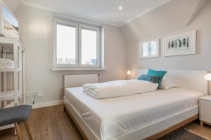 a bedroom with a white bed with two windows at Sylter Inselglück in Wenningstedt