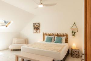 a white bedroom with a bed and a chair at Villa du Ruisseau in Saint-Louis