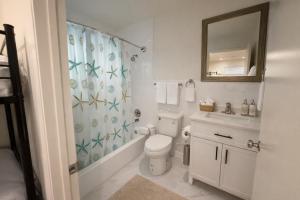 a bathroom with a toilet and a sink and a mirror at The Olympic Suites LA in Los Angeles
