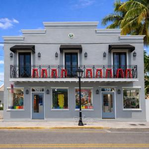 a white building with red chairs on a balcony at Yellowfin Ledge in Key West
