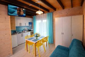 a kitchen with a table and yellow chairs and a tv at Morska Przygoda in Rewal