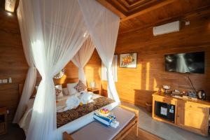 a bedroom with a bed with curtains and a tv at The Patra Villa Sebatu by Dhananjaya Hospitality in Tampaksiring