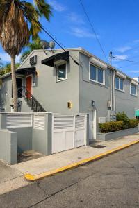 a gray house with a white fence and palm trees at Pescado Penthouse in Key West