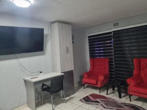 a living room with two red chairs and a tv at Tana B Guesthouse in Welkom