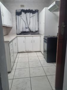 a kitchen with white cabinets and a window at Tana B Guesthouse in Welkom