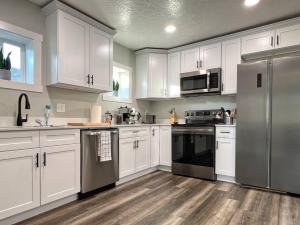 a kitchen with white cabinets and stainless steel appliances at Sun & Snow Bungalow Remodeled Hot Tub W&D in South Salt Lake +43 photos