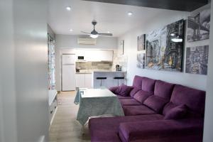 a living room with a purple couch and a table at Apartamentos turísticos ilusiones in Cazalla de la Sierra
