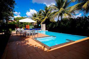 a pool with a table and chairs and an umbrella at Hotel das Palmeiras in Paracatu