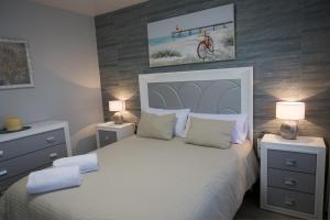 a bedroom with a white bed with two night stands and two lamps at Apartamentos turísticos ilusiones in Cazalla de la Sierra