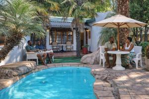 a group of people sitting around a table by a pool at Lodge At The Link in Kempton Park