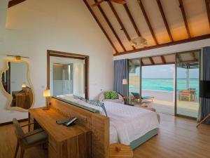 a bedroom with a bed and a desk with a mirror at Meyyafushi Maldives - Premium All Inclusive in Lhaviyani Atoll