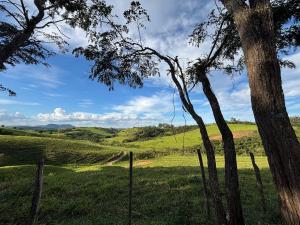 a field with a fence and a tree at Mountain View Guesthouse: Peaceful Retreat near Tiradentes in Prados +9 photos