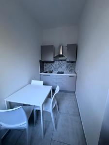 a kitchen with a white table and white chairs at Domus - Casa Vacanze in Cinquefrondi +11 photos