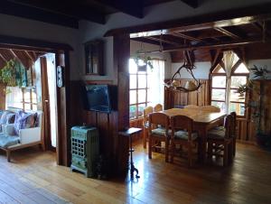 a dining room with a table and a tv at Casa Patagónica con Vista al Lago y Jardín Ideal Familias en Bariloche in San Carlos de Bariloche