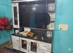 a living room with a large tv and a table at Joyful Homestay in Mysore