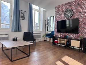 a living room with a brick wall and a flat screen tv at Le Gambetta Théâtre de Calais in Calais