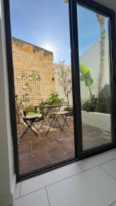 ein Fenster mit Blick auf eine Terrasse mit Tisch und Stühlen in der Unterkunft Happy Hive in Żejtun