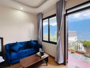 a living room with a blue couch and a large window at Sapa Odyssey Hostel in Sapa +33 photos