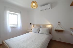 a bedroom with a white bed and a window at Townhouse with Rooftop Terrace in Olhão in Olhão
