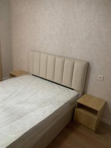 a bed in a room with a stool next to it at E&L Apartment tbilisi in Tbilisi City