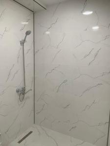 a bathroom with a shower with white marble walls at E&L Apartment tbilisi in Tbilisi City +14 photos