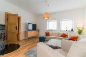a living room with a white couch and a tv at Lykke Suite in Handewitt