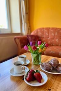 a table with two cups of coffee and strawberries and flowers at Bauernhuus 4 in Fehmarn