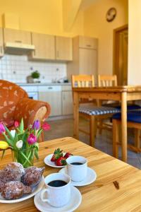 a wooden table with two cups of coffee and pastries at Bauernhuus 4 in Fehmarn