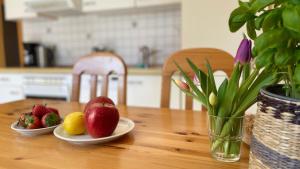 two plates of fruit on a wooden table with a vase at Backhuus 1 in Fehmarn