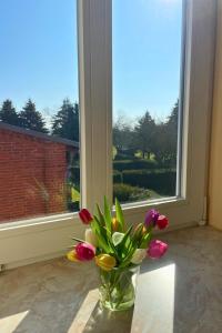 a vase of flowers sitting on a table in front of a window at Bauernhuus 5 in Fehmarn +31 photos