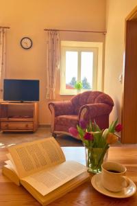 a living room with a table with a book and flowers at Bauernhuus 5 in Fehmarn