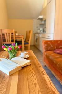 a table with a book and a vase of flowers on it at Bauernhuus 5 in Fehmarn