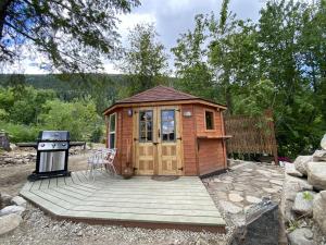 a wooden cabin with a grill on a wooden deck at Boho Bungalow in Nelson