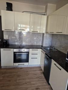 a kitchen with white cabinets and a black appliance at Garden of Eden- MintGarden- Sveti Vlas in Sveti Vlas