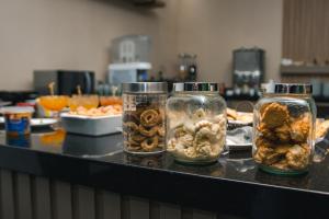 a counter with four jars filled with different types of food at Hotel Rota 090 in Piraí do Sul