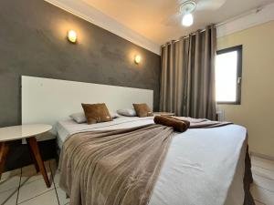 a bedroom with two beds and a table at GoHost Suítes - 2 Ruas do Shopping Santa Úrsula in Ribeirão Preto
