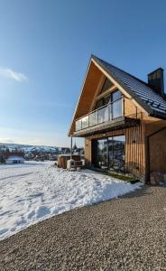 a wooden house with a balcony in the snow at Allure Chalet, z prywatnym jacuzzi, z widokiem na góry in Dzianisz