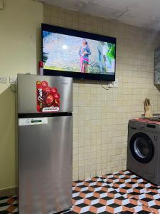a television hanging on a wall with a refrigerator at ALFUTTAIN Vacation Homes Rental in Dubai