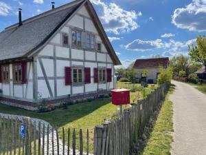 a white house with red shutters and a fence at Fischerhaus Godewind 45 qm Studio in Altwarp