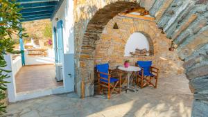 a patio with a table and chairs in a stone wall at Villa Art Natalie two in Kithnos
