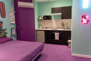 a purple room with a bed and a kitchen at Capsule Tattoo Love - Balnéo - Playstation 5 - écran géant in Douai