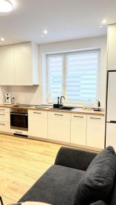 a kitchen with white cabinets and a couch in a room at MICKIEWICZ HOUSE Apartamenty in Wadowice +41 photos