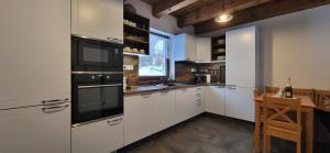 a large kitchen with white cabinets and a window at Chata Krpko in Horná Lehota