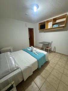 a bedroom with a bed and a table with a chair at Pousada Refúgio da Ilha in São Mateus