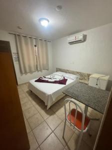 a bedroom with a bed and a table with a chair at Pousada Refúgio da Ilha in São Mateus +3 photos