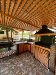 a patio with an outdoor kitchen with a wooden pergola at Hotel Parcela Tierra Fértil in Coltauco