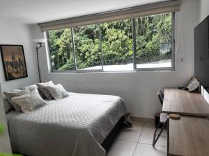 a bedroom with a bed and a large window at Cálido mini apartamento in Manizales