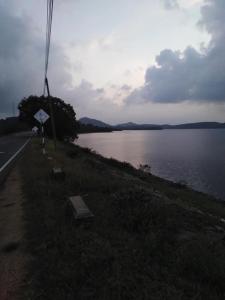 a road next to a body of water at Lake parth Giritale in Giritale