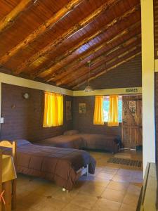 ein Schlafzimmer mit zwei Betten und einer Holzdecke in der Unterkunft Cabañas Atrapasueños in Trevelín